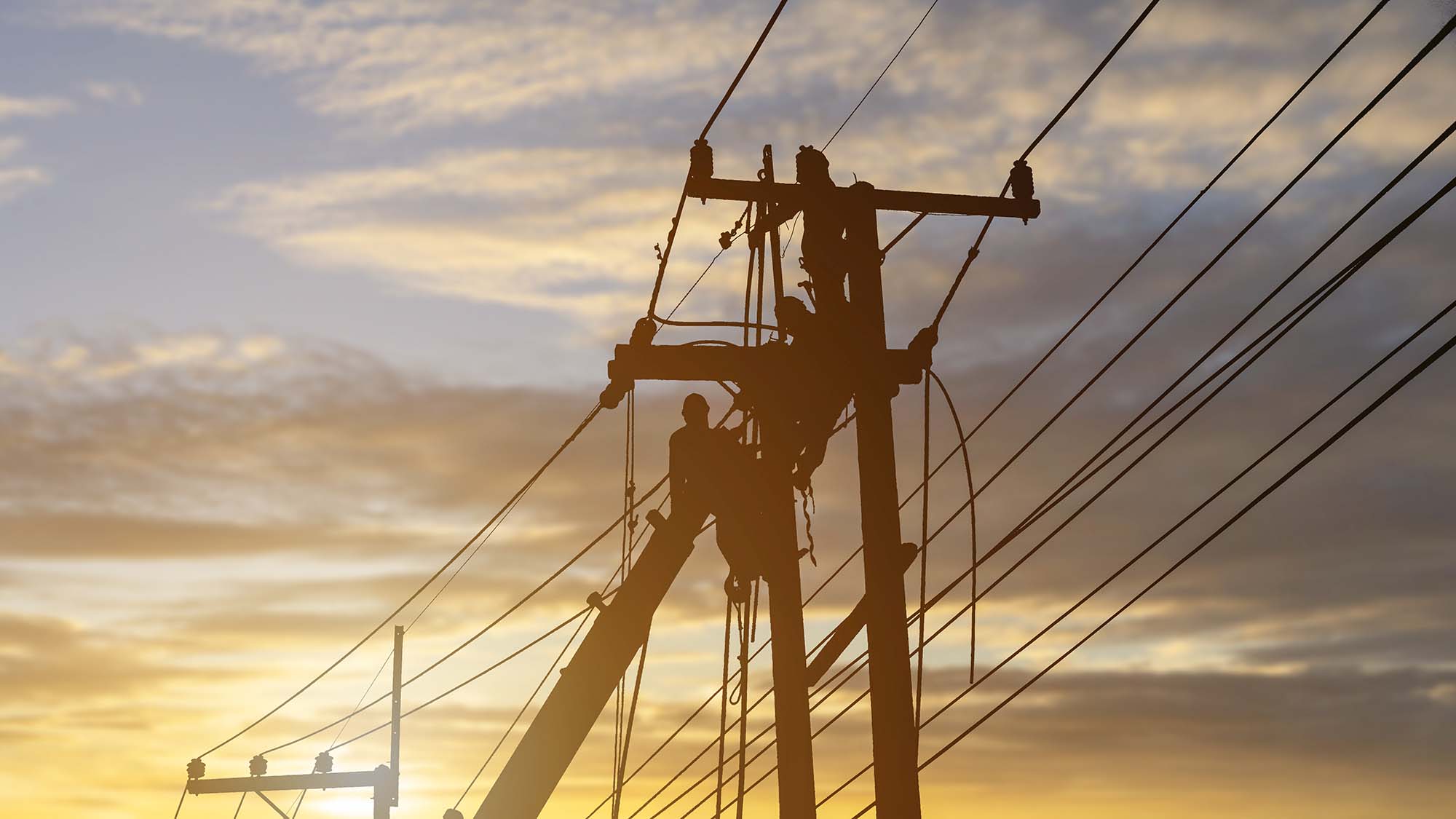 Electricians work on high voltage towers to install wires and equipment.